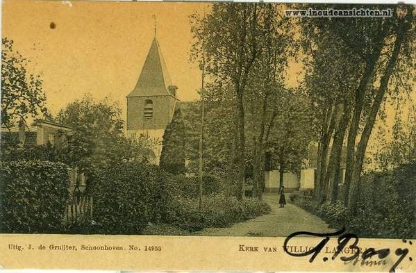 De kerktoren gezien door de bomen langs de laan